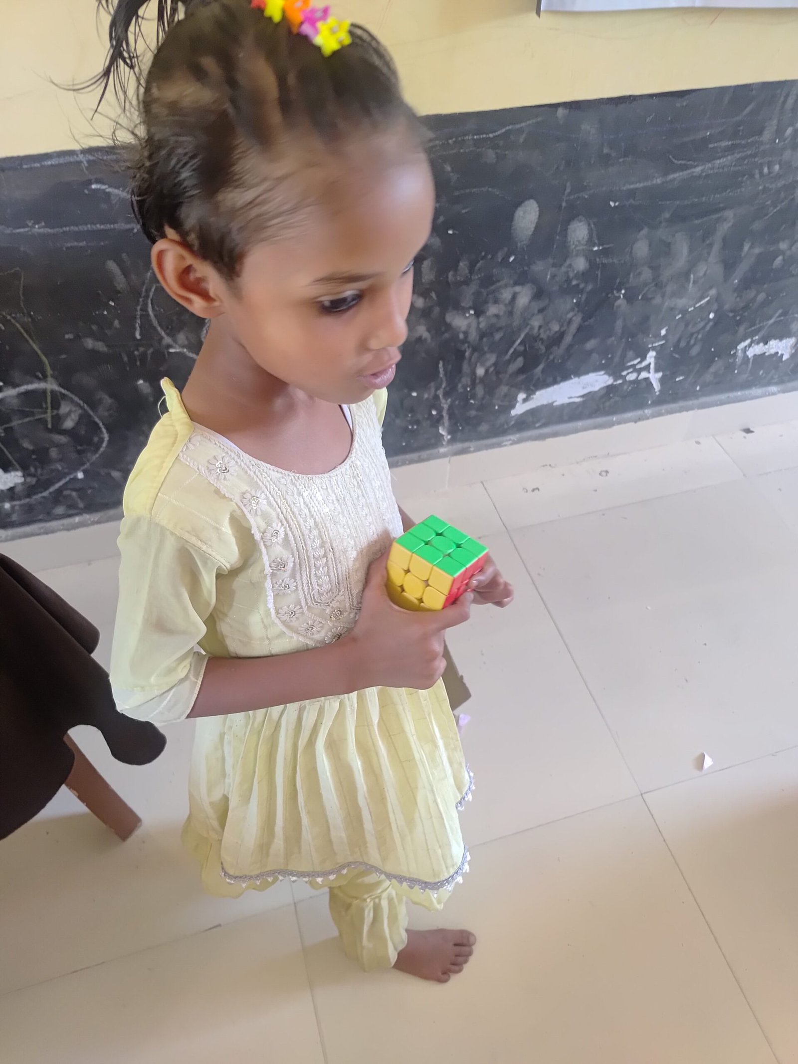 बच्चे रेत में अक्षर लिखते हुए सीखते हुए